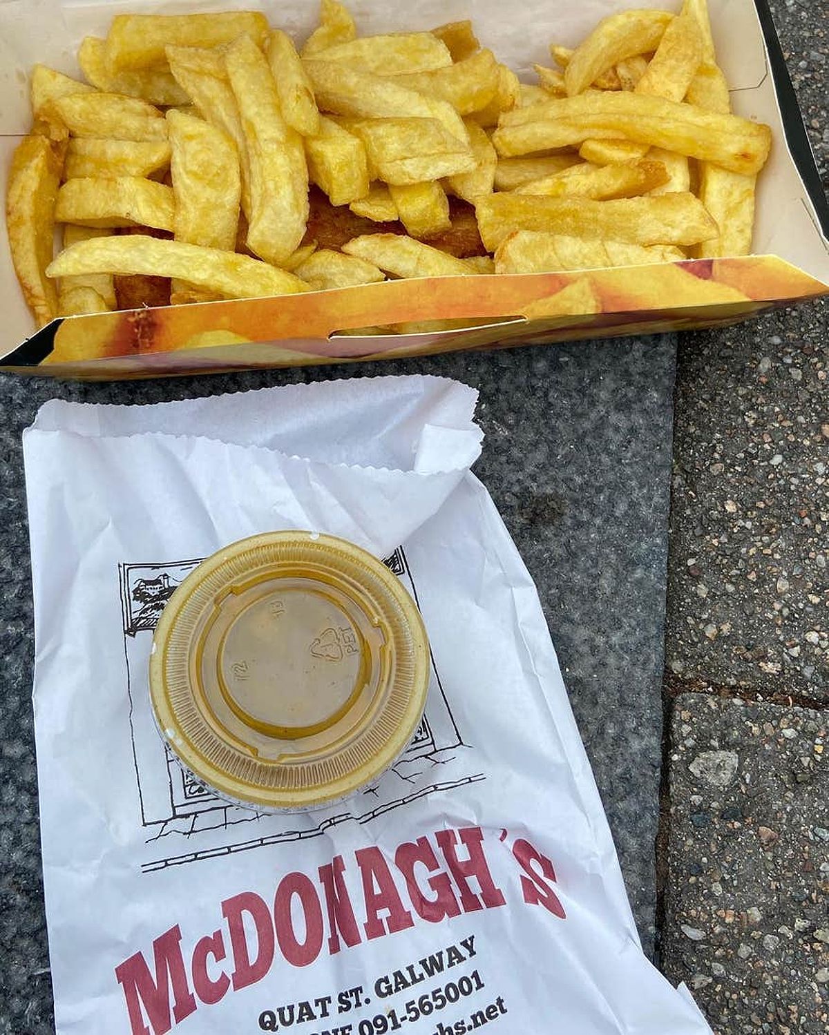 A container of chips with a tub of sauce