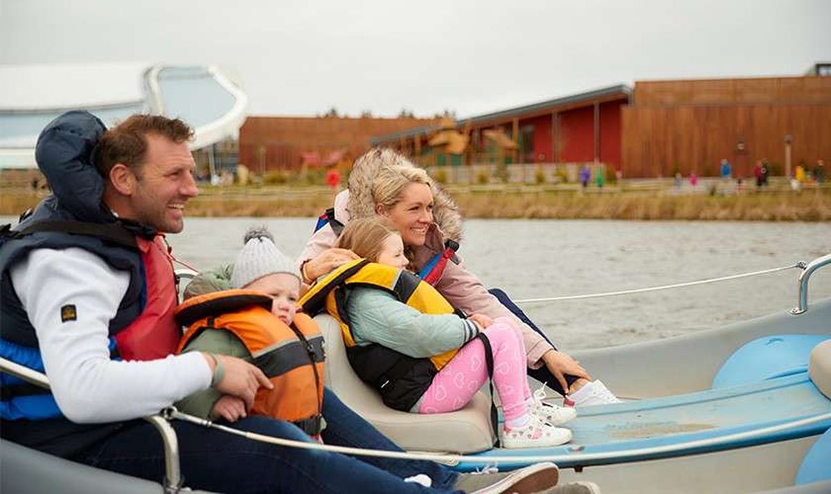 Family on an electric boat on the lake at Longford Forest