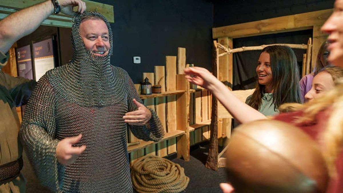 Man wearing chain mail with family at the Knights and Conquests Heritage Centre